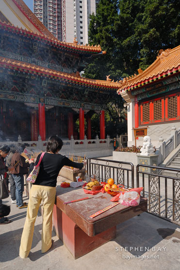 Woman placing incense. Wong Tai Sin Temple, Hong Kong, China.
