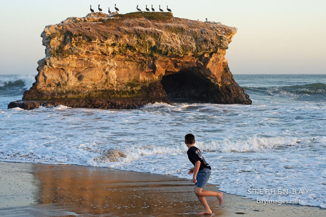 Boy running at Natural bridges state beach, California, USA.