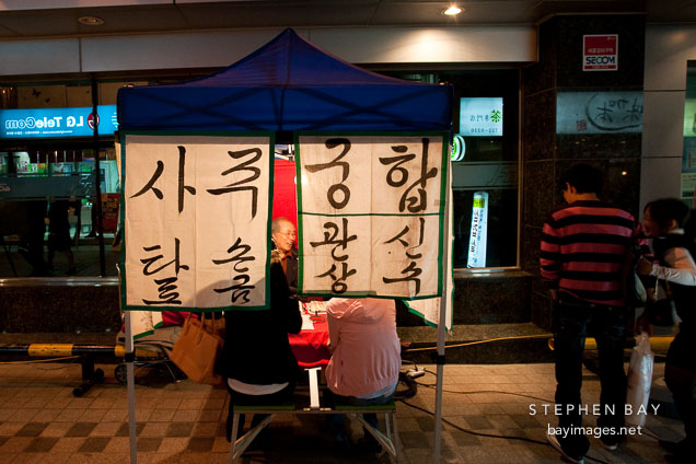 Fortune telling booth with two vistors on a Seoul sidewalk.