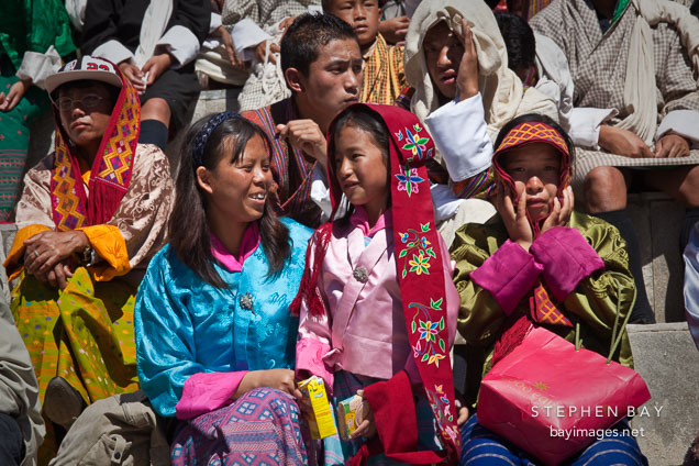 Young girl and mother sitting in the crowd at Thimphu tsechu festival.