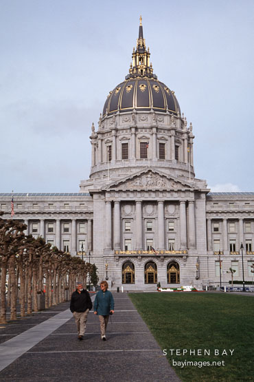 Couple walking by City Hall on an overcast morning. San Francisco, California, USA.