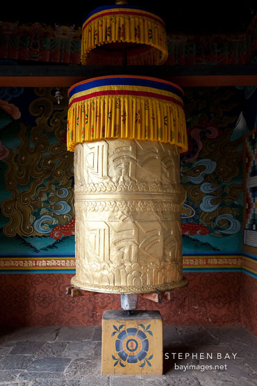 Large golden prayer wheel at the entrance to Punakha Dzong. Punakha, Bhutan.