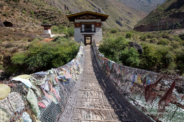 Restored iron bridge with sides covered in prayer flags. South of Paro, Bhutan.