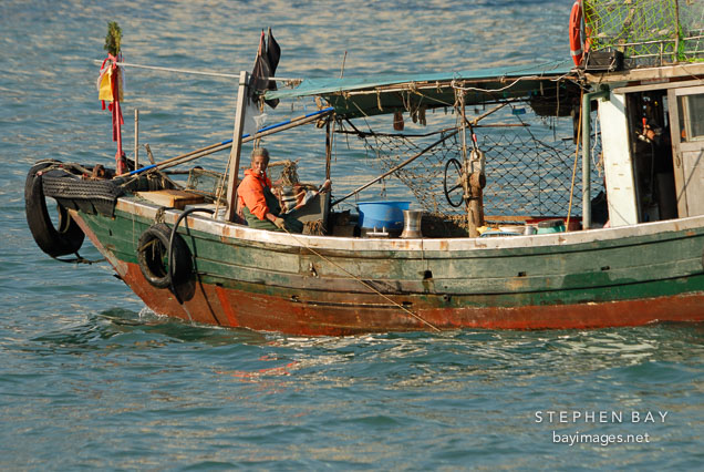 Man on fishing boat in Victoria Harbor. Hong Kong, China.