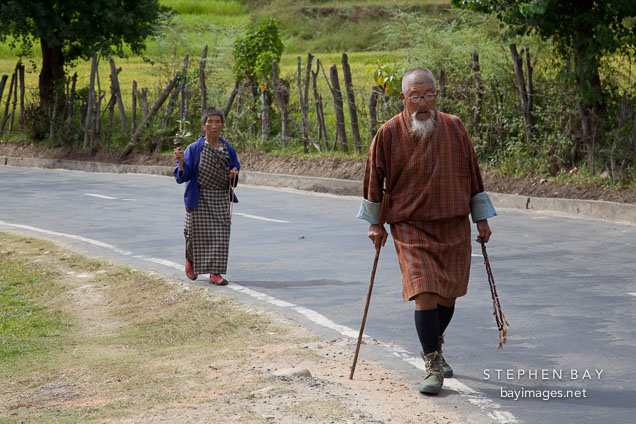 Man and woman walking along the road by Punakha Dzong. Punakha, Bhutan.