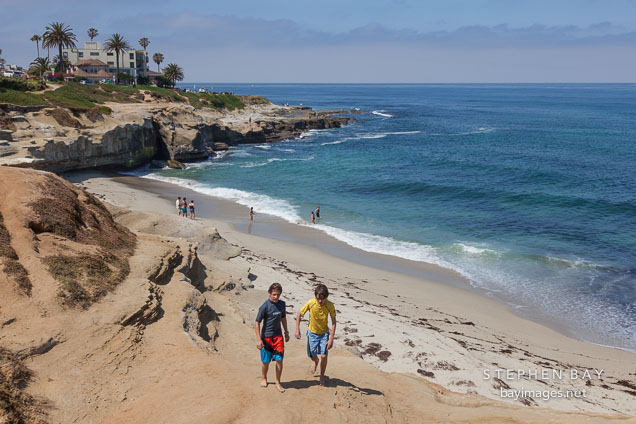 Two boys walking on the beach at La Jolla. La Jolla, California.