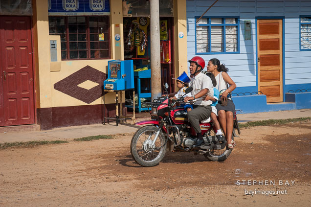 Family riding a motorcycle taxi. Puerto Maldonado, Peru