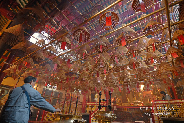 Man placing incense in pot. Man Mo Temple, Hong Kong, China.