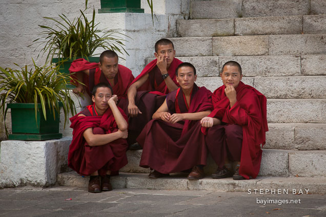 Young Buddhists monks sit on the steps just outside the courtyard at the fortress. Thimphu tsechu, Bhutan.