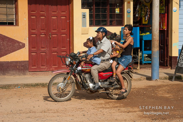 Mother and children riding a motorcycle taxi. Puerto Maldonado, Peru