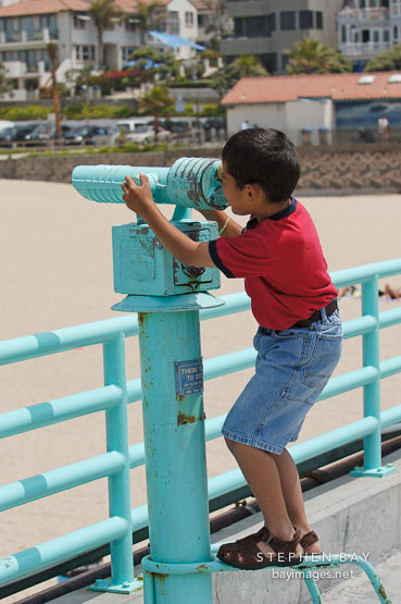 Boy using binoculars. Manhattan Beach, Los Angeles, California, USA.