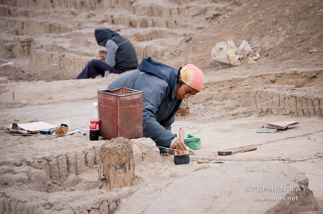 Woman brushing dirt during an excavation at Huaca Pucllana, an adobe pyramid. Lima, Peru.