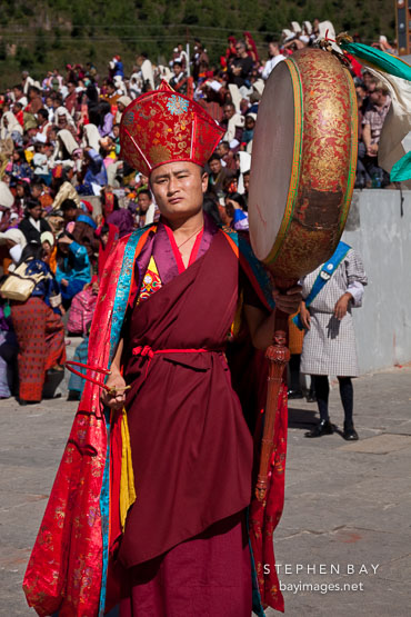 Monk walking in a procession and beating drum. Thimphu tsechu, Bhutan.