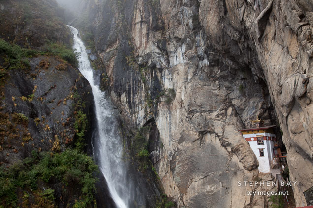 Waterfall (Shelkar Zar) and Singye Phu Lhakhang near the Tiger's Nest monastery. Paro Valley, Bhutan.