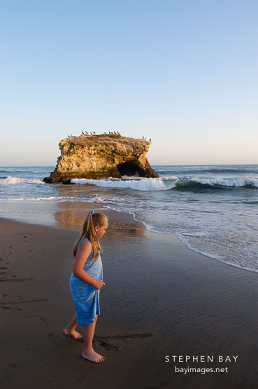 Girl walking in the sand at Natural bridges state beach, California, USA.