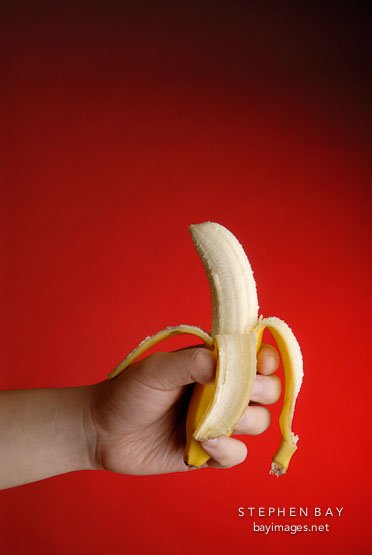 Banana in hand with red background