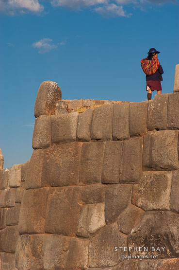 Peruvian woman atop stone wall. Sacsayhuaman. Peru.