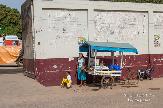 Young woman and child running with a vegetable stand. Puerto Maldonado, Peru.