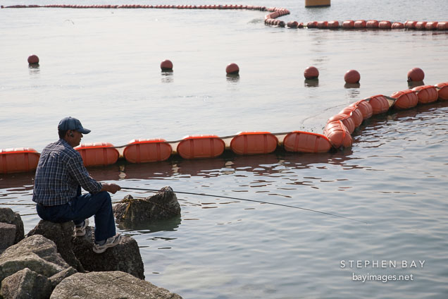 A fisherman perches on the rocks in Wolmido, Incheon, South Korea.