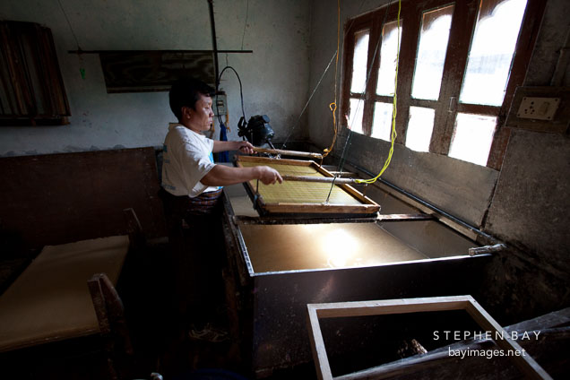 Man using wooden frame and bamboo screen to obtain a thin layer of pulp. Jungshi Handmade Paper Factory, Thimphu, Bhutan.