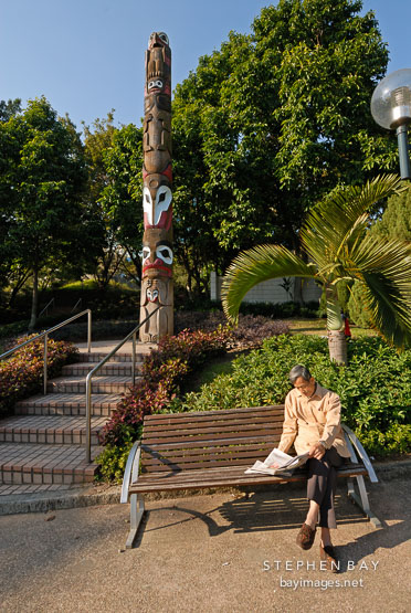 Man reading newspaper. Kowloon park, Hong Kong, China.