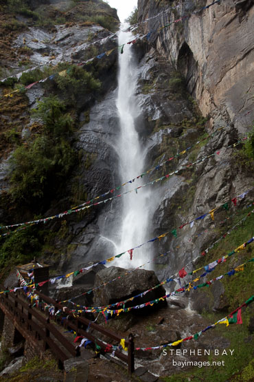 A bridge takes travelers past the Shelkar Zar waterfall to Taktshang. Paro Valley, Bhutan.