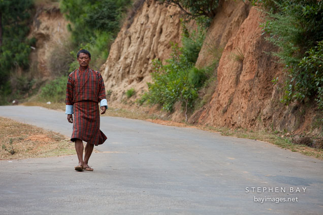Man walking to town along the road. Punakha, Bhutan.