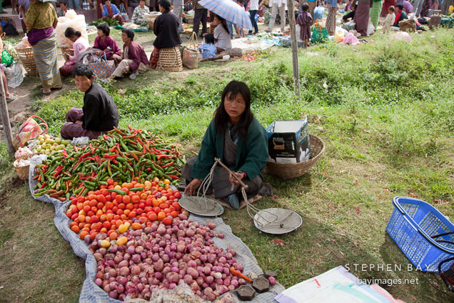 Woman selling onions, tomatoes, and chili peppers at the weekend market. Punakha, Bhutan.