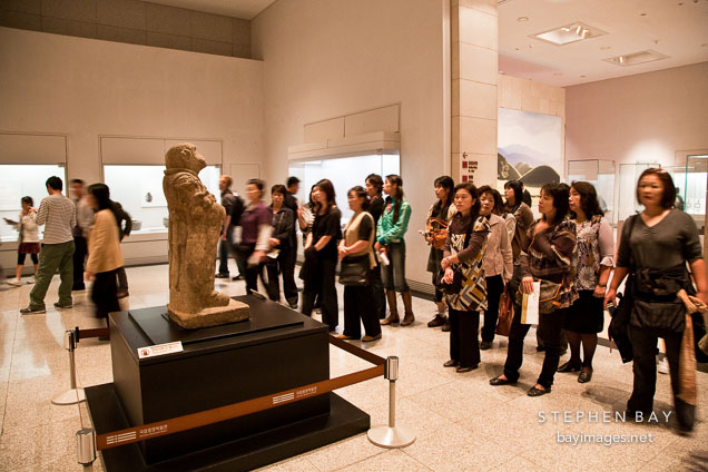 Visitors to the National Museum of Korea gather around a stone zodiacal figurine representing a monkey from the 8th century.