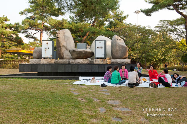 Women enjoy a picnic in front of artist Erik Dietman's sculpture, Yesterday and the Day Before Today and Tomorrow, at Olympic Park in Seoul, South Korea.