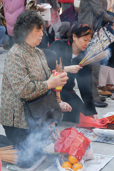 Woman shaking fortune sticks. Wong Tai Sin Temple, Hong Kong, China.