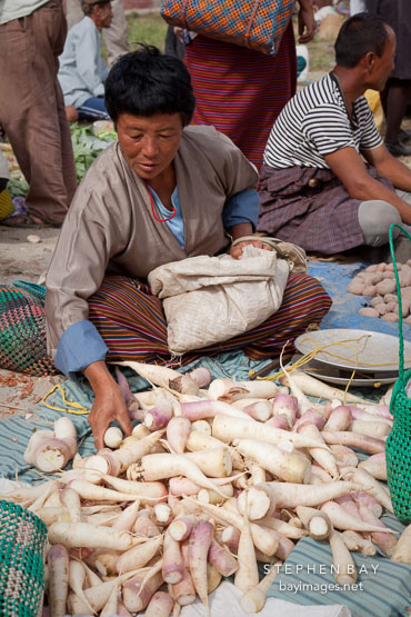 Woman with daikon radishes at the weekend market. Punakha, Bhutan.