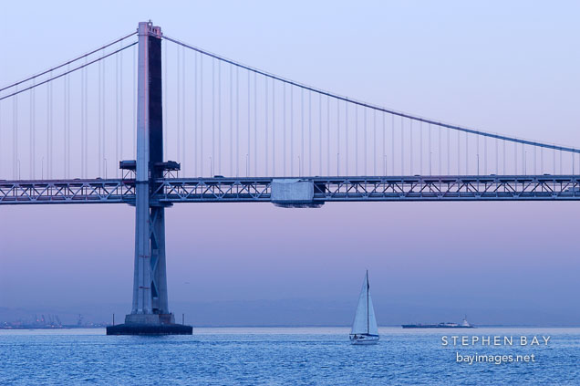 Sailboat and the Oakland Bay Bridge, at dusk. San Francisco, California.