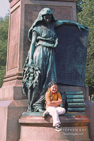 Girl sitting at the statue of the Patron muse of Finnish poetry. Runebergin esplanadi, Helsinki, Finland.