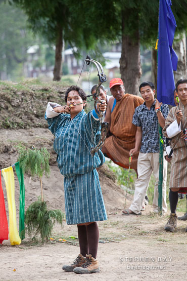 Man with drawn bow takes aim during an archery competition. Punakha, Bhutan.