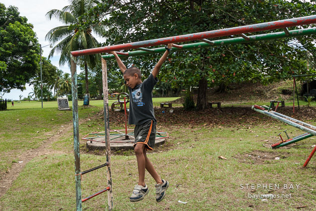 Boy hanging from bars. Tortuguero village, Costa Rica.