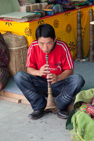 Young man playing the lingm, a traditional Bhutanese flute. Thimphu, Bhutan.