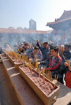 Lighting incense to honor their ancestors. Wong Tai Sin Temple, Hong Kong, China. - Photo #15742