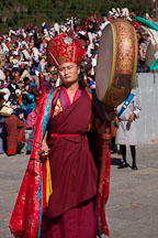Monk walking in a procession and beating drum. Thimphu tsechu, Bhutan. - Photo #22444