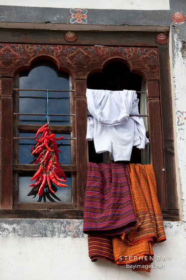 Window with chili peppers and clothes. Thimphu, Bhutan.
