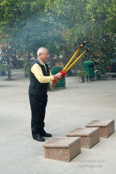 Man burning joss sticks. Po Lin Monastery, Hong Kong, China.