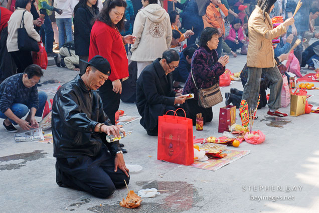 Man offering alcohol and food for the deceased. Wong Tai Sin Temple, Hong Kong, China.