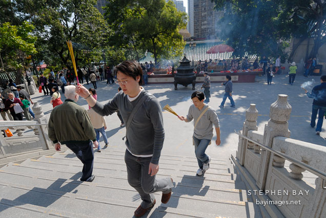 Visitor carrying burning incense. Wong Tai Sin Temple, Hong Kong, China.