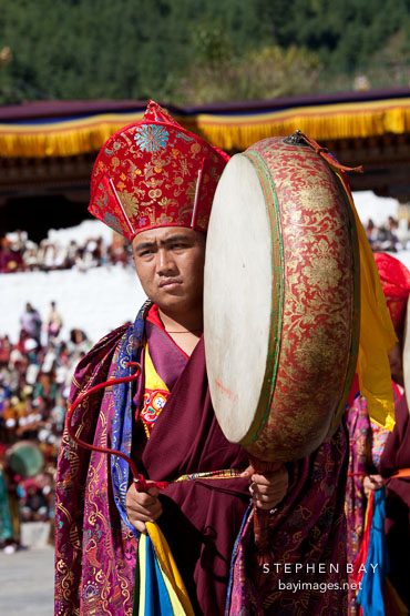Monks in elaborate robes beat drums in the last morning procession at Thimphu tsechu. Bhutan.