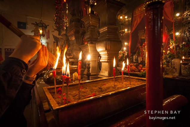 Lighting incense with candles. Man Mo Temple, Hong Kong, China.
