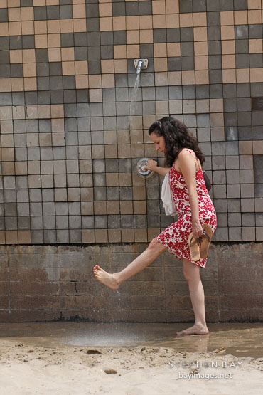 Young woman washing her feet. Manhattan Beach, Los Angeles, California, USA.