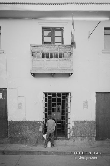 Boy in front of locked door. Cusco, Peru.