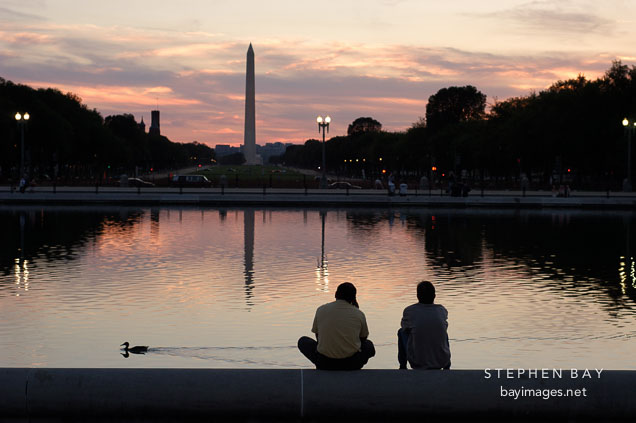 Friends sitting by the Capitol reflecting pool. Washington Monument. Washington, D.C.