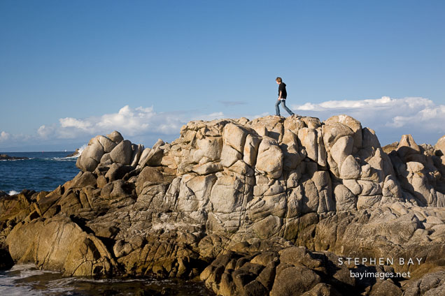 Teenager hiking over coastal rocks. Pacific Grove, California.
