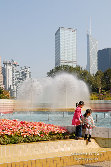 Two girls by the fountain in Hong Kong Park. Hong Kong, China.
